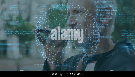 Speaking IT expert holding smartphone at mouth at park courtyard, with code overlay, copy space Stock Photo