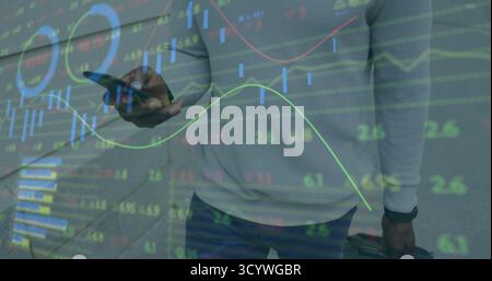 Man in casual business attire analyzing financial graphs on walkway, with smartphone and suitcase Stock Photo