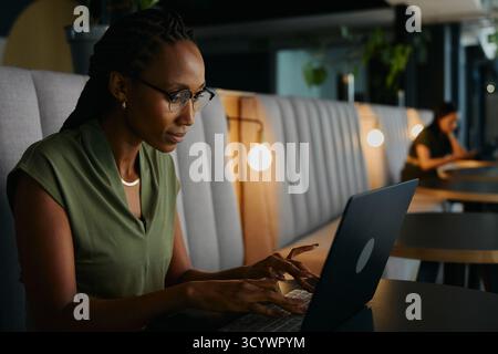 Focused young black businesswoman typing on laptop sitting at desk in office lounge Stock Photo