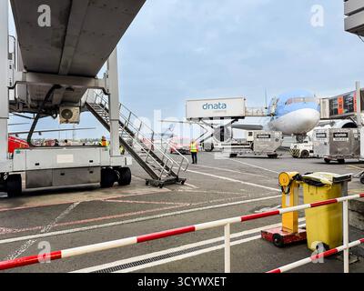 Ground crew at an airport preparing a  Tui aircraftfor departure with equipment, carts, and passenger boarding bridge in view Stock Photo