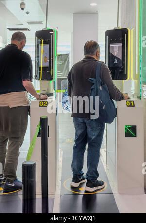 Two men stand at electronic self-check-in kiosks in newcastle international airport, using technology for entry. EES new system Stock Photo