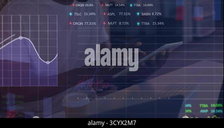 Analyzing financial analyst reviewing tablet at office desk, with keyboard, virtual stock charts Stock Photo
