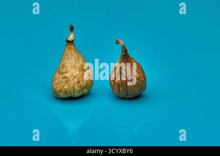 Studio still life photo of two dried figs on blue background. Natural earthy colors contrast with vibrant surface creating clean modern healthy food c Stock Photo