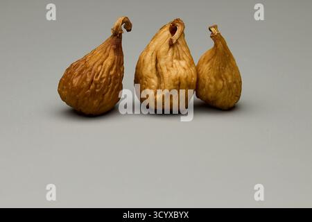 Studio photo of three dried figs arranged on gray background. Natural texture of dried fruit with soft diffused lighting and minimal composition ideal Stock Photo