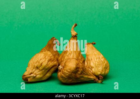 Minimal food composition showing three dried figs on bright green background. Earthy textures and organic color contrast perfect for natural food and Stock Photo