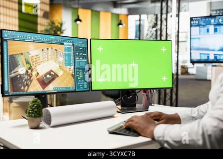 Male developer decorating apartment layout on 3D software next to green screen display, working with interior design tools for residential decorations project. Real estate management. Stock Photo