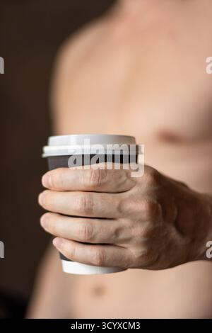 Hands Holding Coffee Cup in Calm Moment. Close-up of male hands cradling a warm coffee cup, symbolizing remote work break, morning hygiene ritual Stock Photo