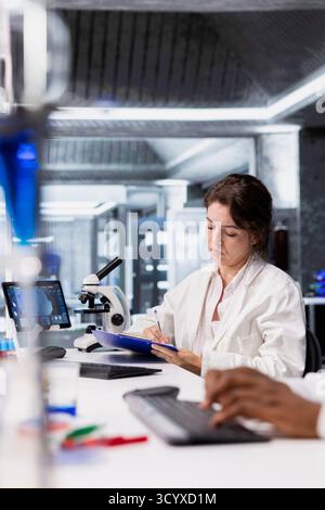 Scientist records observations from laboratory experiment for research documentation and scientific publication. Woman in lab doing data logging, taking notes, preparing clinical reports Stock Photo