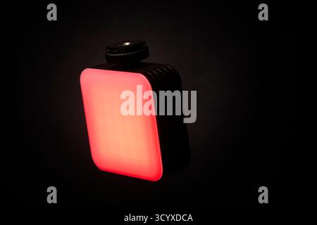 A compact red LED light panel photographed on a black background with bright glowing surface. The image highlights its rectangular design ideal for ph Stock Photo