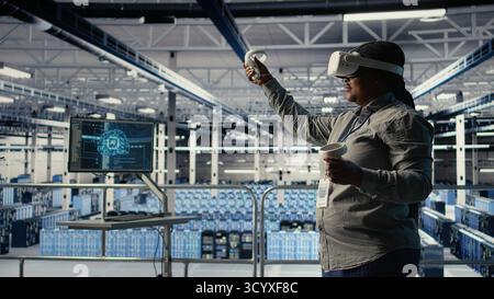 Data center technician using virtual reality, improving AI rigs processing speed. Server hub IT expert using VR headset to manage gear providing support for artificial intelligence workloads, camera A Stock Photo