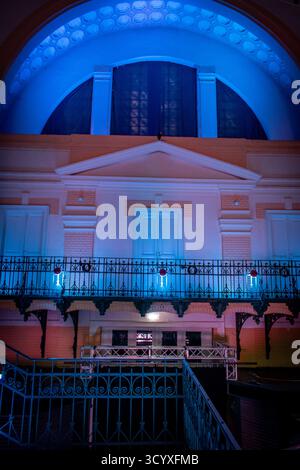 An industrial-style interior with metal beams, railings, and a tiled floor, all illuminated by colorful lights. Stock Photo
