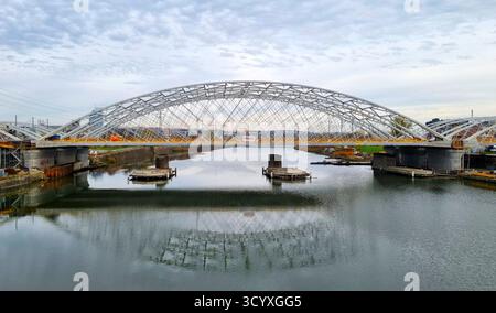 Openwork Podgórzanek Bridge under construction and its reflection in the Vistula River, Krakow, Poland Stock Photo