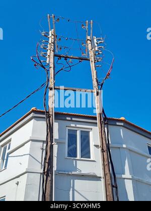 A three-phase high-voltage switchgear on wooden poles mounted on a building Stock Photo