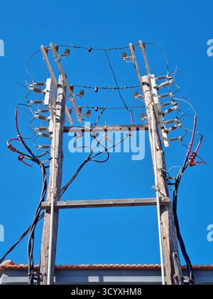 Outdated design of the three-phase high-voltage switchgear on wooden poles Stock Photo