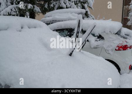 Cars completely covered with thick snow after a heavy snowfall in a residential parking area. Stock Photo