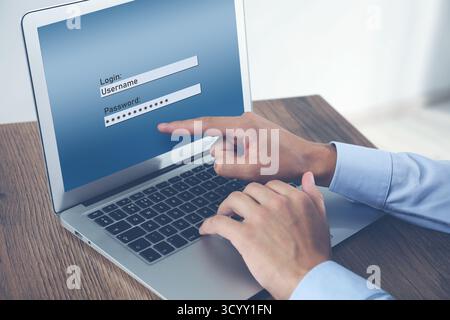 Man entering password to sign in to user account on laptop at table, closeup Stock Photo