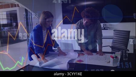 Analyzing colleagues in shirt and blazer reviewing blueprints modern office, with laptop and notes Stock Photo