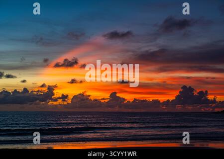 A breathtaking view of a fiery sunset sky with layers of deep red, orange, and golden clouds glowing above the horizon, capturing the serene beauty of Stock Photo