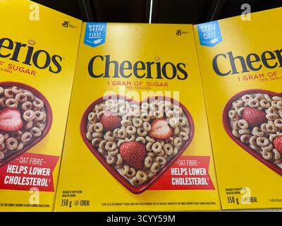 Cheerios cereal boxes displayed in a grocery store aisle, featuring health claims and a heart-shaped bowl with cereal and strawberries on the packagin Stock Photo
