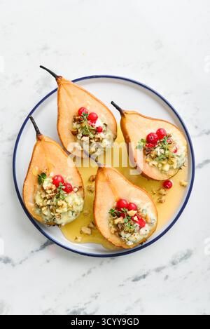 Delicious baked pears with nuts, blue cheese, thyme, cranberry and honey on light background, top view Stock Photo