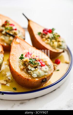 Delicious baked pears with nuts, blue cheese, thyme, cranberry and honey on light background closeup Stock Photo