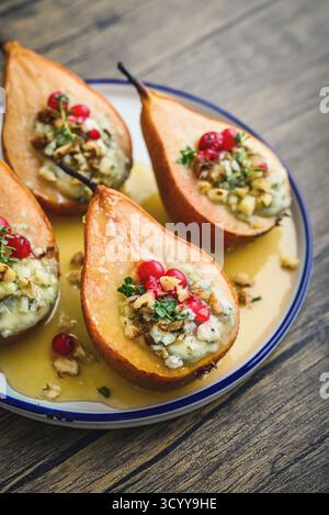 Delicious baked pears with nuts, blue cheese, thyme, cranberry and honey on wooden table closeup Stock Photo