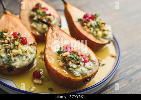 Delicious baked pears with nuts, blue cheese, thyme, cranberry and honey on wooden table closeup Stock Photo