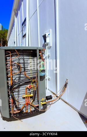 Technicians are performing maintenance on an outdoor HVAC unit, exposing its internal components Stock Photo