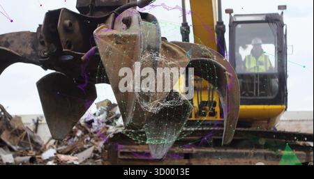 Grabbing steel scraps excavator claw operating in scrap yard, showing operator hard hat and vest Stock Photo