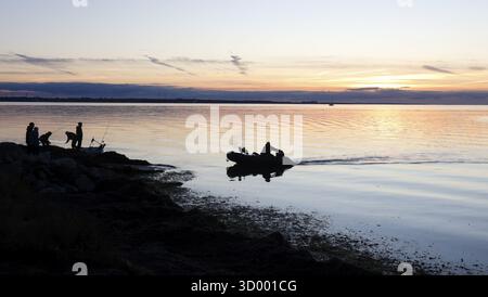 Angler on the beach during sunset, an angler docks on the shore with his inflatable boat and dog, Fehmarn island, 18.10.2025, Fehmarn, Schleswig-Holst Stock Photo