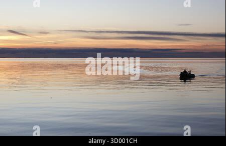 Angler on the beach during sunset, an angler docks on the shore with his inflatable boat and dog, Fehmarn island, 18.10.2025, Fehmarn, Schleswig-Holst Stock Photo