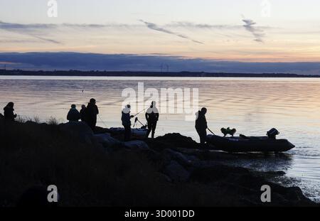 Angler on the beach during sunset, an angler docks on the shore with his inflatable boat and dog, Fehmarn island, 18.10.2025, Fehmarn, Schleswig-Holst Stock Photo
