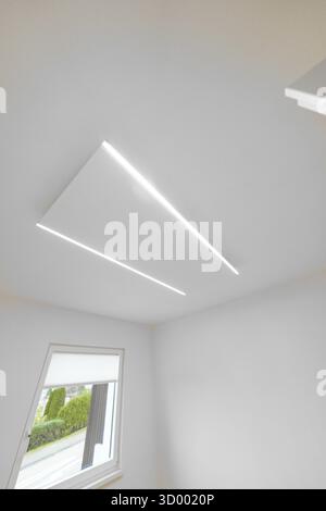 Modern white ceiling with two slim LED lines, geometric light detail near window, house renovation, climate renovation, Metzingen, Germany Stock Photo