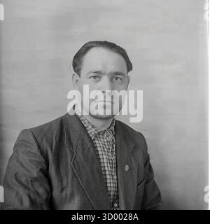 This 1966 archival photo is a formal portrait of a middle-aged man from Sloviansk, Ukrainian SSR, likely a factory worker or engineer. The head-and-shoulders shot captures him looking directly at the camera with a serious expression. He wears a plaid shirt under a dark jacket, with a small badge pinned to the lapel. This straightforward image is a typical example of Soviet-era portraiture, capturing the dignity and character of the working people who were the backbone of industry in the peaceful Donbas Stock Photo