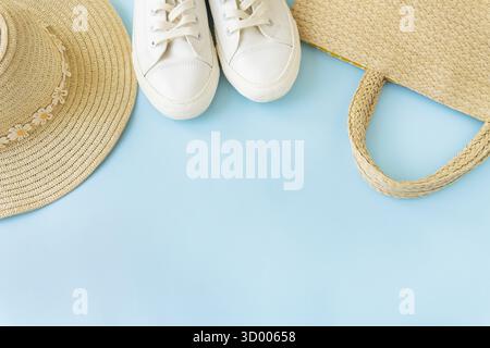 This look features summery pieces on a blue background: white sneakers, a straw hat, and a woven bag. Items are arranged aesthetically, with space for Stock Photo