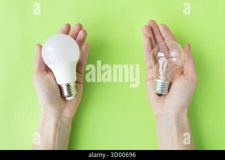 A set of two types of lamps, LED and incandescent, in the hands of a girl isolated on a green background. Energy-saving lamps Stock Photo
