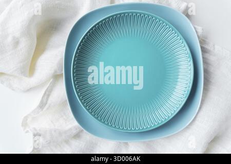A vibrant blue plate on a white cloth. The cloth underneath is textured and appears soft and delicate. There s a contrast between the bold color of th Stock Photo