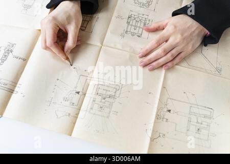 This image shows hands reviewing architectural blueprints for construction or renovation. The plans are detailed and contain various designs and layou Stock Photo
