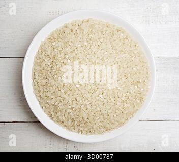 Top view of uncooked rice in glass bowl on wooden background Stock Photo