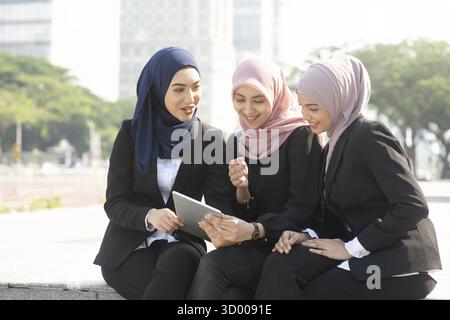 Group of Muslim business women discussing, using tablet pc outdoor Stock Photo