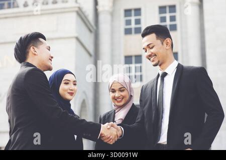 Businesspeople hand shaking, standing in front office building, multiracial business concept Stock Photo