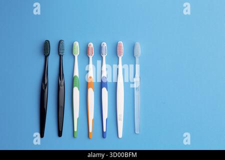 Multi-colored toothbrushes on blue background, place for inscription Stock Photo