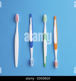 Four multicolored toothbrushes on empty blue background Stock Photo
