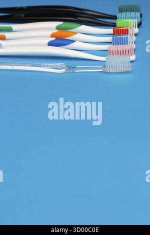 Photo of multi-colored toothbrushes on top of empty blue background, place for inscription Stock Photo