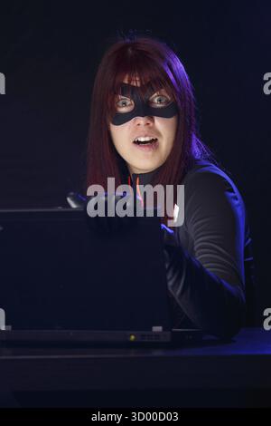 Brunette wearing mask at night stealing information from laptop Stock Photo