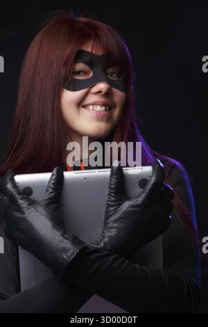 Smiling thief in black gloves holding laptop Stock Photo
