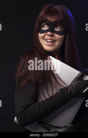Hacker with long hair in mask holds laptop Stock Photo