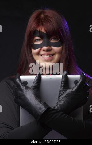 Beautiful hacker in black gloves holds laptop Stock Photo
