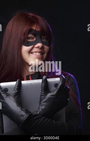 Beautiful thief in black gloves holds laptop Stock Photo