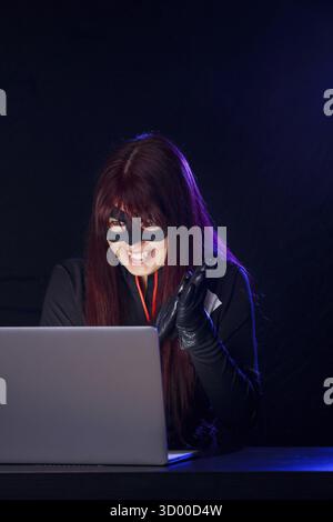Night photo of hacker girl sitting behind laptop Stock Photo